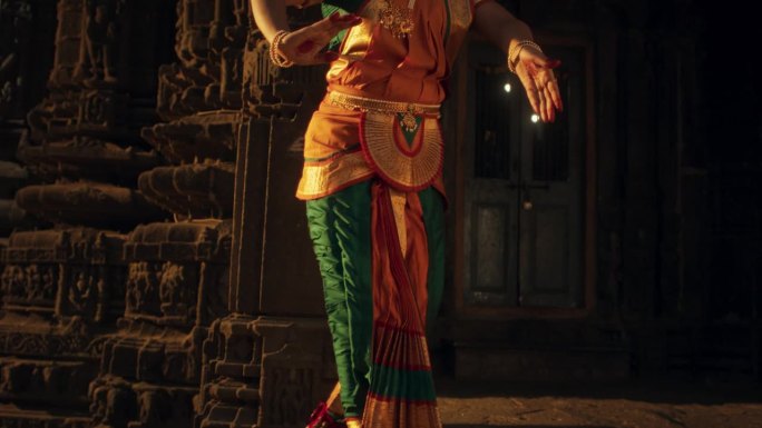 一位印度妇女的肖像，优雅地展示了巴拉塔纳塔姆舞蹈的腿部动作，穿着传统服装。古庙中南亚民族舞蹈与文化之