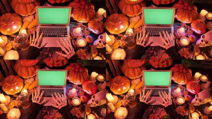 俯视图:瘦骨嶙峋的怪物双手在笔记本电脑键盘上打字，绿色屏幕上有许多雕刻的橙色传统南瓜，