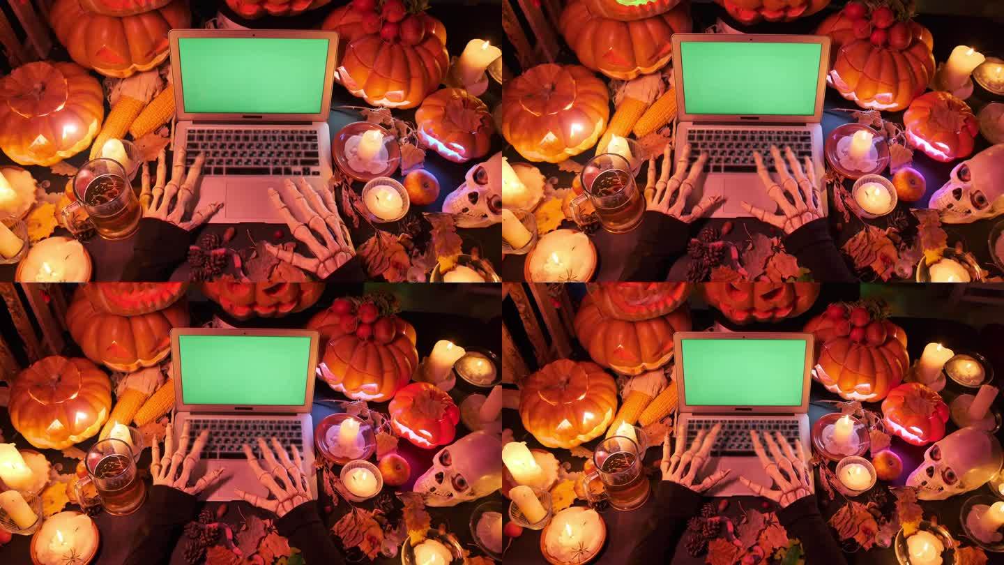 俯视图:瘦骨嶙峋的怪物双手在笔记本电脑键盘上打字，绿色屏幕上有许多雕刻的橙色传统南瓜，