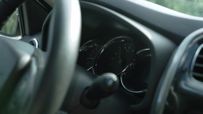 在汽车行驶过程中，转速表上的箭头平稳下降，特写。