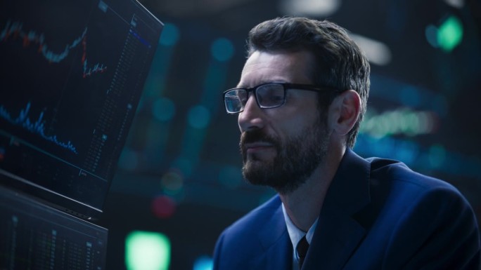 一个聪明而体贴的证券交易所经纪人的特写肖像。戴眼镜的成年男子看着电脑屏幕，分析股票交易市场数据，集思