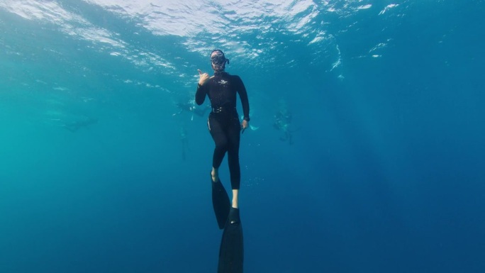 一名自由潜水员在水下游泳，慢慢地接近水面