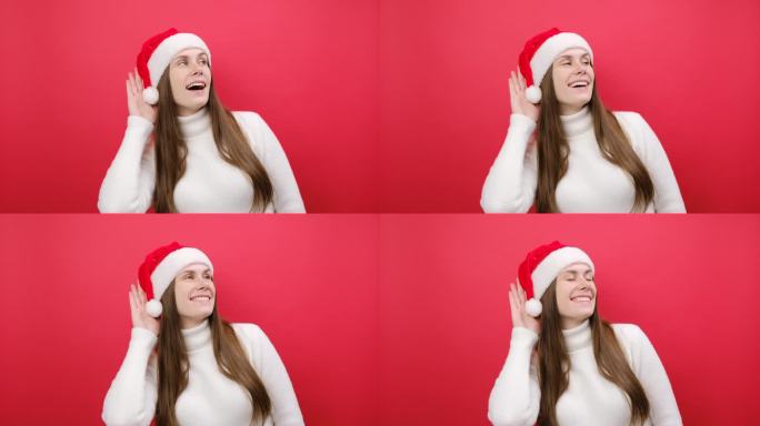 好奇的爱管闲事的年轻女子穿着温暖的白色毛衣，戴着圣诞老人帽，试着听你偷听，在工作室里淡红色的背景下独
