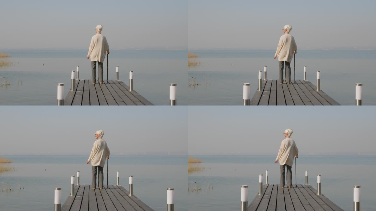 老妇人站在木码头上看湖