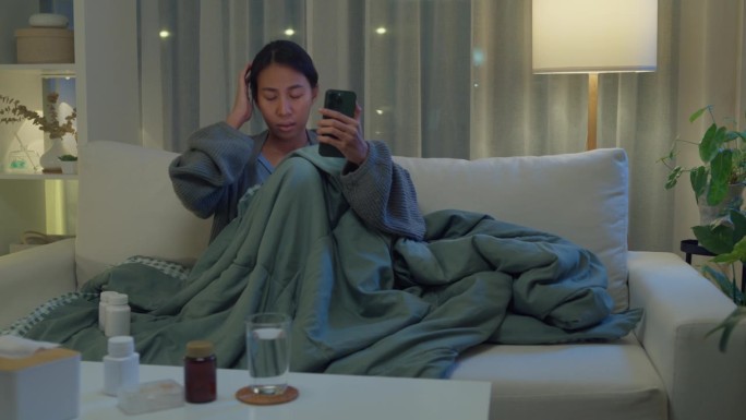 年轻的亚洲女孩患者通过手机视频通话咨询医生，在医疗app上进行药物剂量说明，晚上在家进行远程医疗在线
