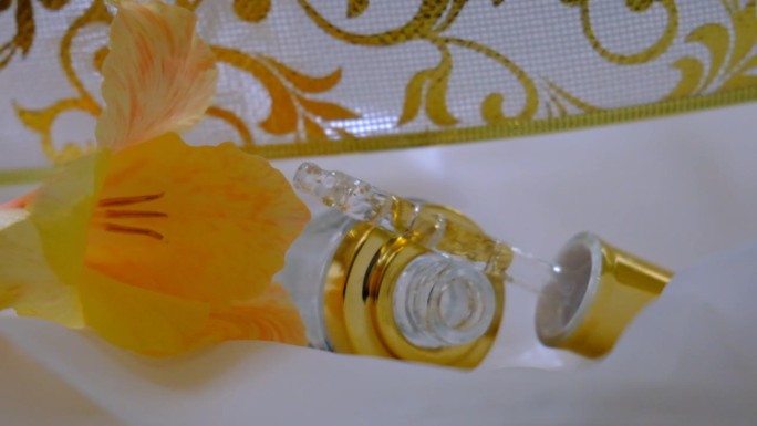 脸部美容油或精华液的特写在透明的滴管瓶，装饰花。玻璃移液管中的玻尿酸