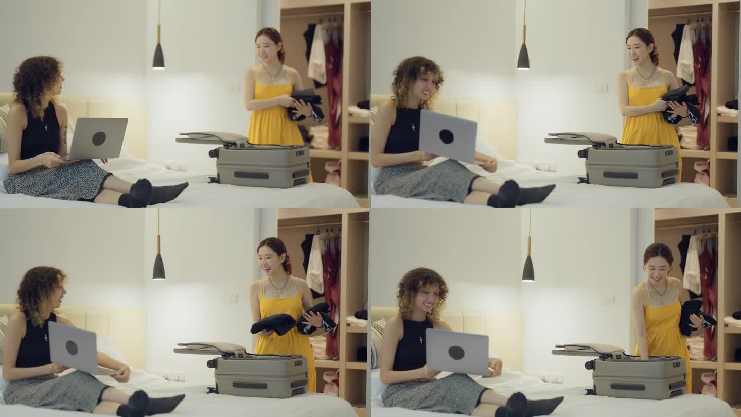 漂亮的亚洲女人在为行李准备衣服，和看着笔记本电脑屏幕计划度假的朋友聊天。