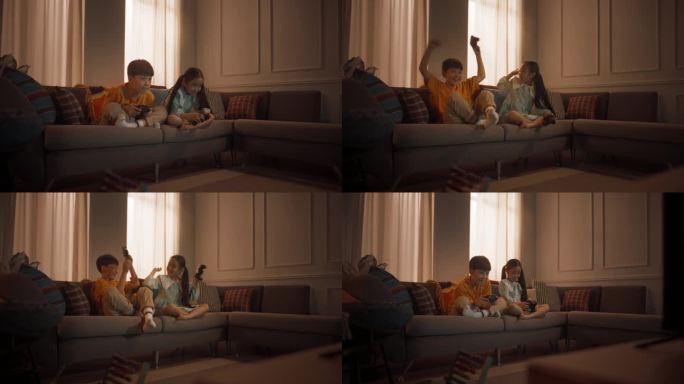 可爱的小兄妹在客厅沙发上的游戏机上玩电子游戏。韩国兄弟姐妹在比赛中获胜，庆祝并互相击掌。放学后玩得开