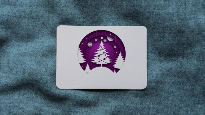 紫色剪纸风格的圣诞树，并在圣诞贺卡上呈现圣诞快乐的文字动画