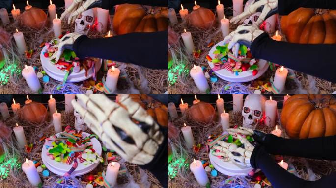 近距离看，瘦骨嶙峋的双手在传统的南瓜蜡烛中变出了万圣节的糖果，旁边是骷髅，神秘的节日背景。