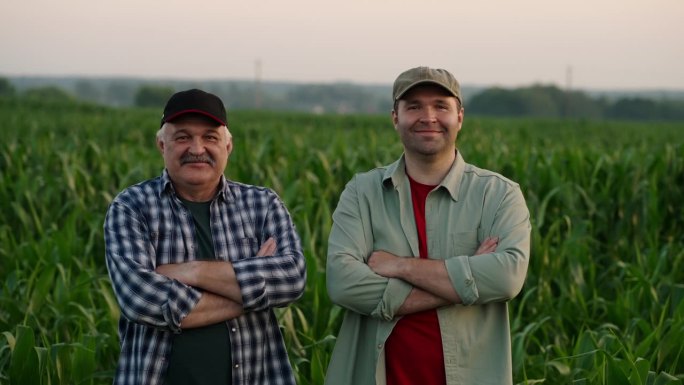 两个快乐的农民在夏天的农田里，男人看着镜头微笑