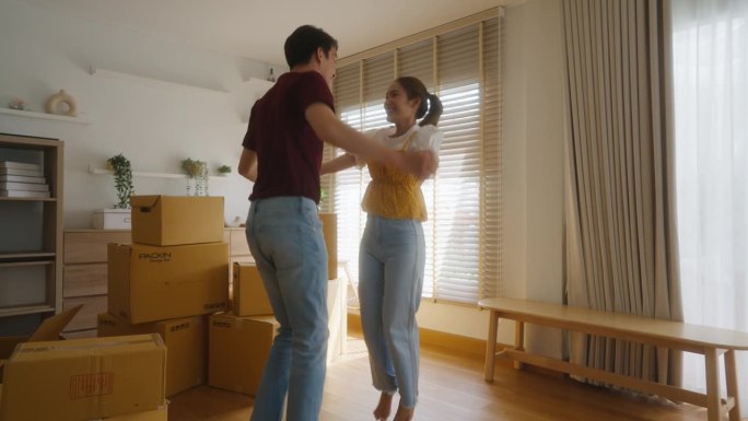 一个年轻的女人抱着她的男朋友开心地买了她自己的房子，在旧房子里堆满了纸箱。为男女夫妇组建家庭