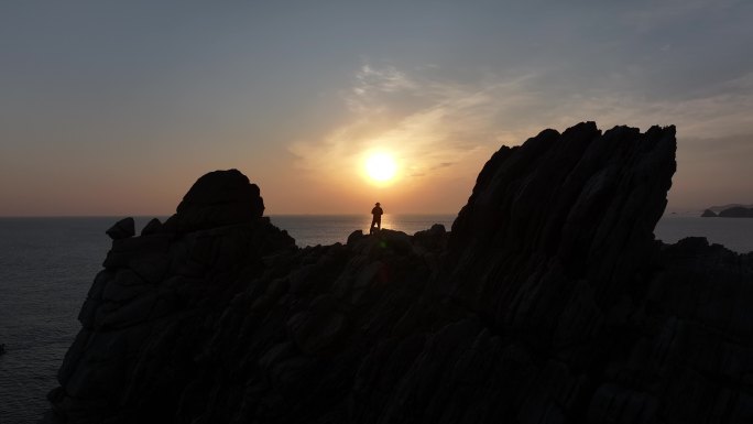 航拍威海市环翠区猫头山海岛礁石日出看海人