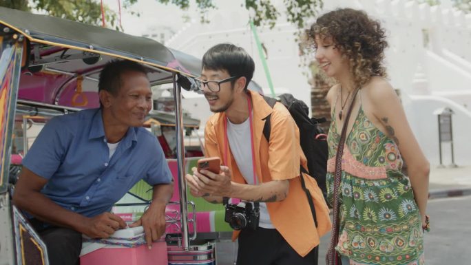 亚洲游客夫妇在曼谷地标附近向当地的嘟嘟车司机问路，然后乘车前往那里。