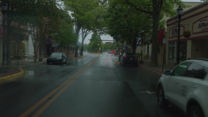 雨中黑暗中的车灯。道路被暴雨浸湿了。汽车行驶在潮湿的W洛克曼街在多佛，德。驾驶牌照，道路的POV