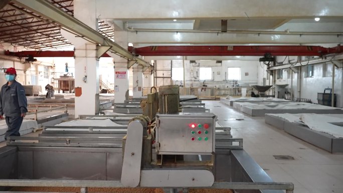 调料厂发酵车间工人用机械搅拌原料发酵池