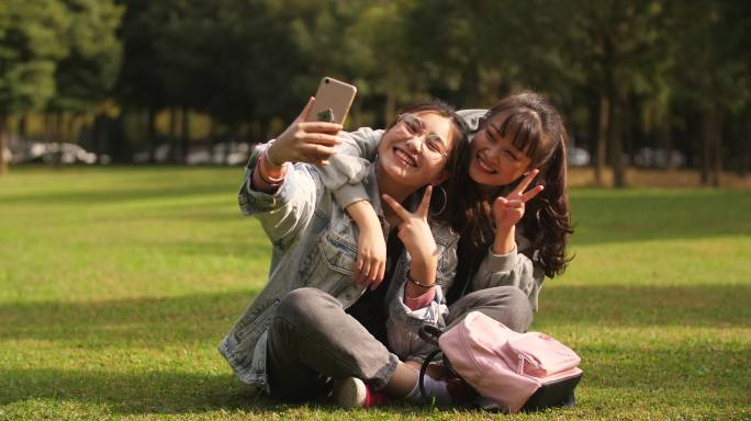 开心闺蜜在大学校园草坪用手机自拍美女可爱