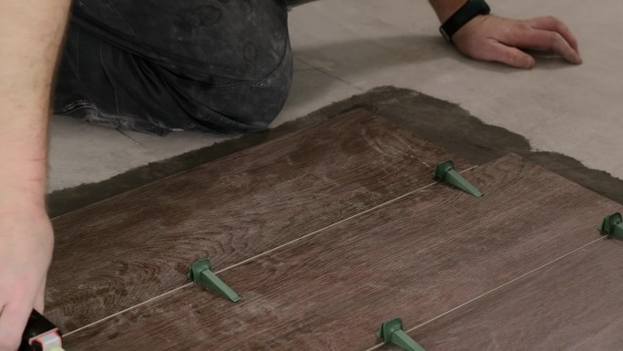 瓷砖放置瓷砖在位置上的粘合剂与鞭打瓷砖找平系统。瓷砖