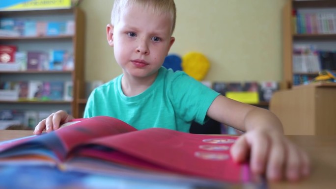 图书馆里的男孩。7岁的乌克兰男孩坐在图书馆的桌子旁看书。学习观念正常，求知欲强，渴望学习新事物。模糊