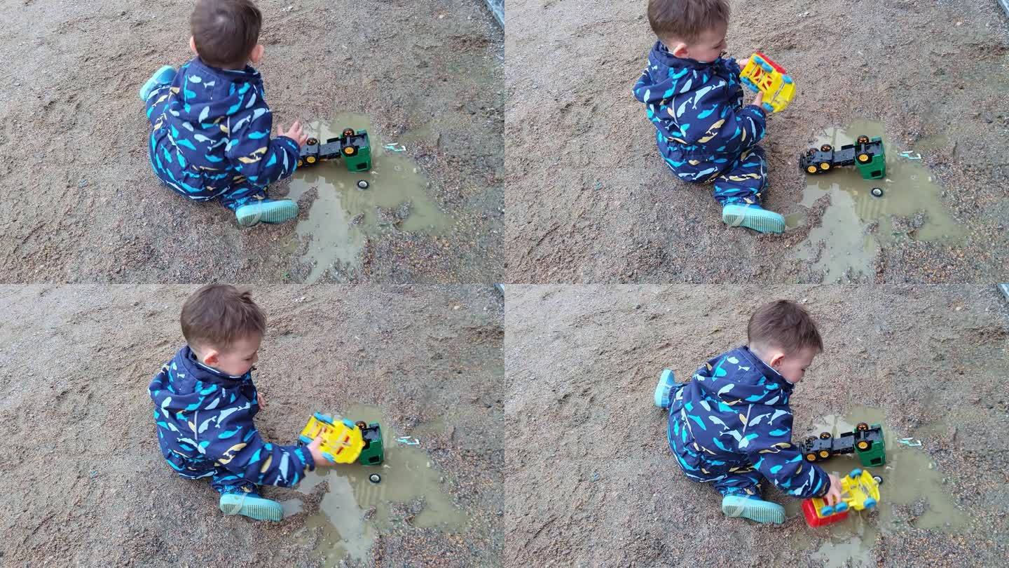 孩子在水坑里玩他的玩具卡车玩得很开心，很享受手上的水和泥的感觉