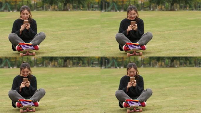 女大学生在大学校园草坪上快乐玩手机上网