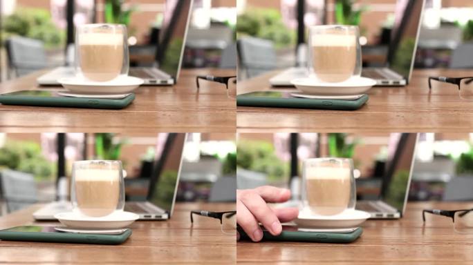 现代锁着的智能手机躺在咖啡桌上，男性的手拿起它。