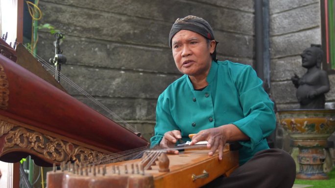 年长的成年人戴着布兰康(一种西爪哇的传统帽子)，穿着传统服装，弹着竖琴或古筝