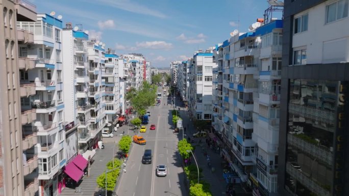 向前飞在宽阔的街道上的商店和公寓大楼。大型住宅区正在崛起。土耳其安塔利亚