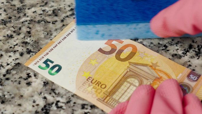 用手洗黑钱，戴上防护手套和海绵。近距离清洗一张50欧元钞票。非法金融行为概念