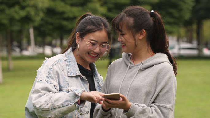 两位女大学生在一起聊天看手机网购学习