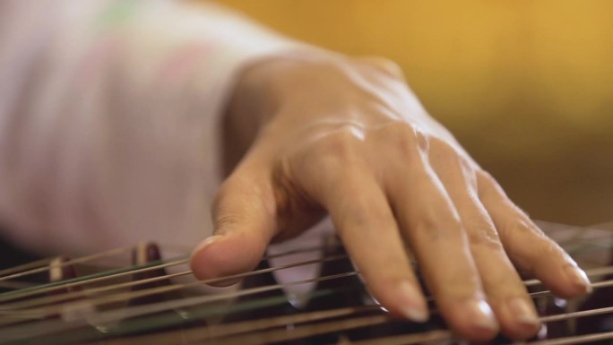 亚洲妇女用手指拨弄竖琴演奏音乐的手