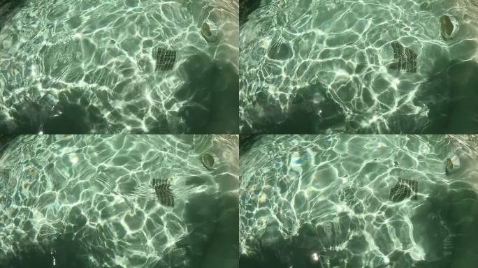 室外游泳池的水波，阳光穿过水面的慢动作场景