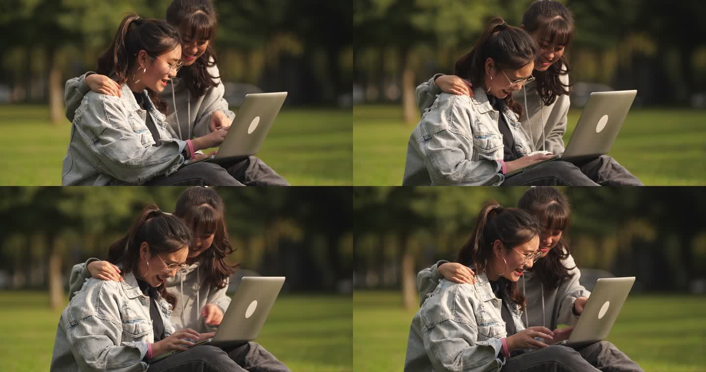两位女大学生坐在校园草地上用电脑讨论学习