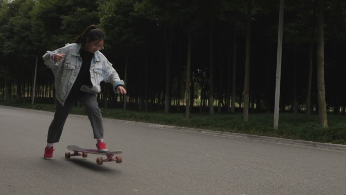 一位女生在校园道路上练习滑板运动