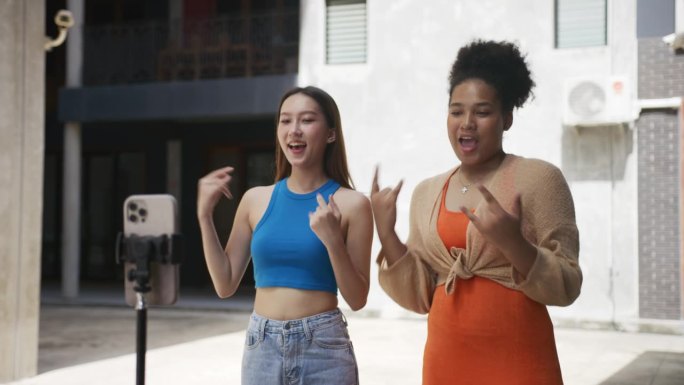 年轻的亚洲朋友跳舞和聊天视频通过智能手机摄像头一起