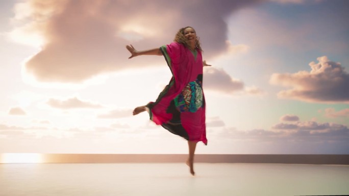 美丽的黑人妇女在非洲服装舞蹈在工作室与天空的背景。创意女性迎镜微笑现代舞编舞