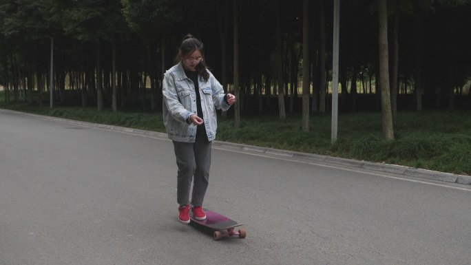 一位女生在校园道路上练习滑板运动