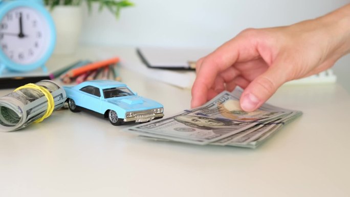 一个女人把一叠钱放在桌子上，旁边是一台微型打字机，视线很浅。汽车保险和贷款的概念。