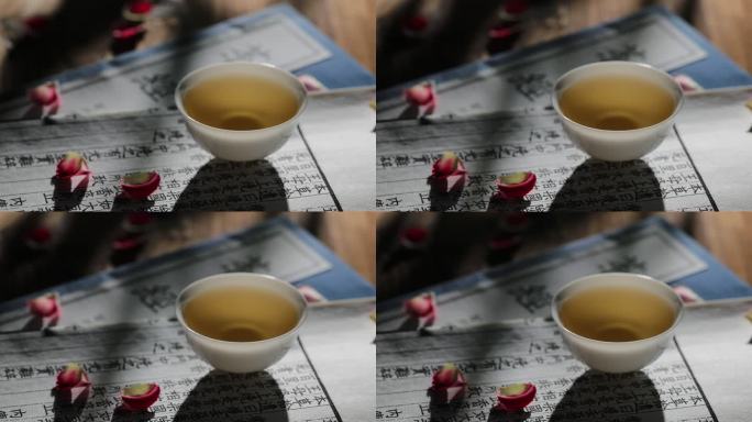 古籍上摆放的一盏茶与散落的花瓣唯美空镜头