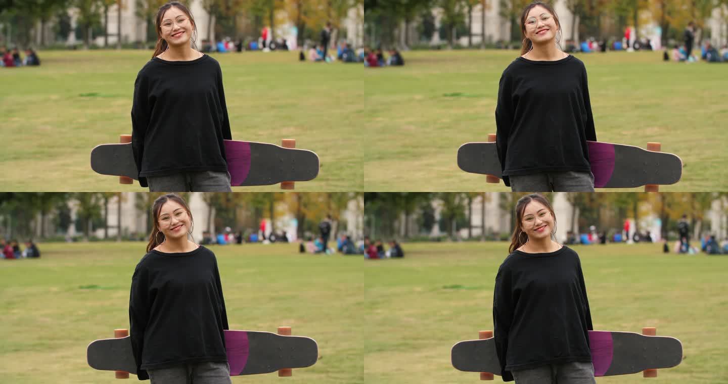 女大学生拿着长板滑板看镜头微笑