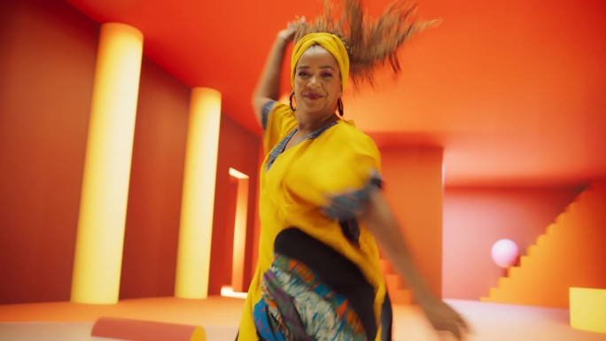 身穿非洲服装的美丽黑人妇女在几何抽象的橙色环境中大力跳舞，庆祝她的文化。创意女性表演现代舞编舞