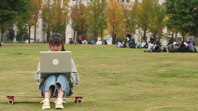 大学校园里女大学生坐在滑板上用电脑学习