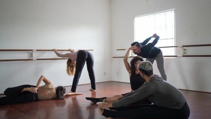 一群人在舞蹈工作室一边聊天一边做伸展运动
