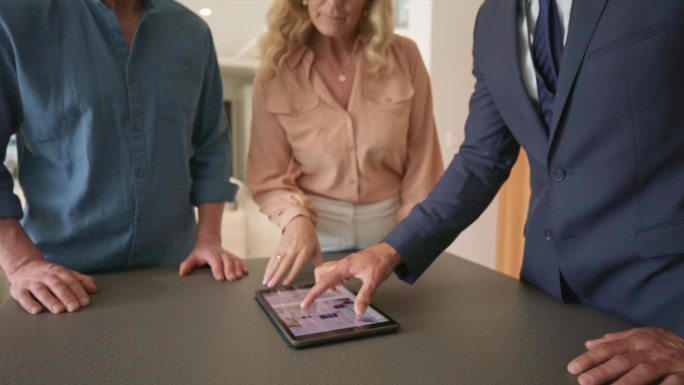 房地产经纪人向一对正在看豪宅的夫妇展示一本电子平板电脑上的小册子