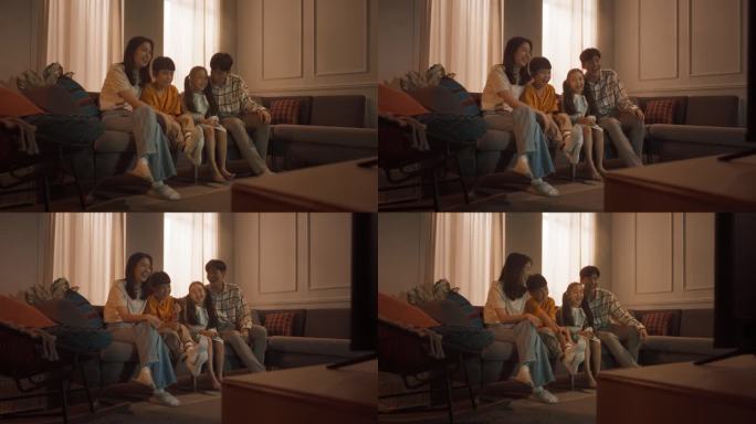 幸福的韩国家庭:妈妈和爸爸在沙发上看着有趣的家庭电视节目，和他们的小儿子和女儿一起笑。兄弟姐妹和父母