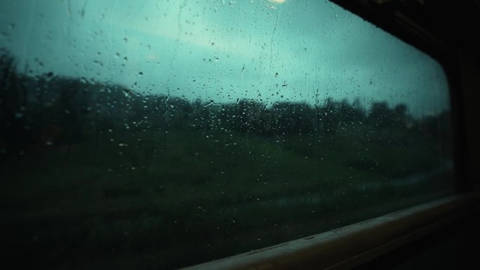 大雨中透过火车窗户看到的壮观景色。雨滴顺着窗玻璃流下来。行驶中的火车窗外下着大雨。在雨中乘火车去山里