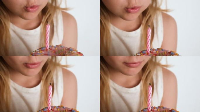 一个女孩吹灭了粉色甜甜圈上的蜡烛。生日快乐或周年纪念的概念。做一个祝福慢动作全高清生日视频