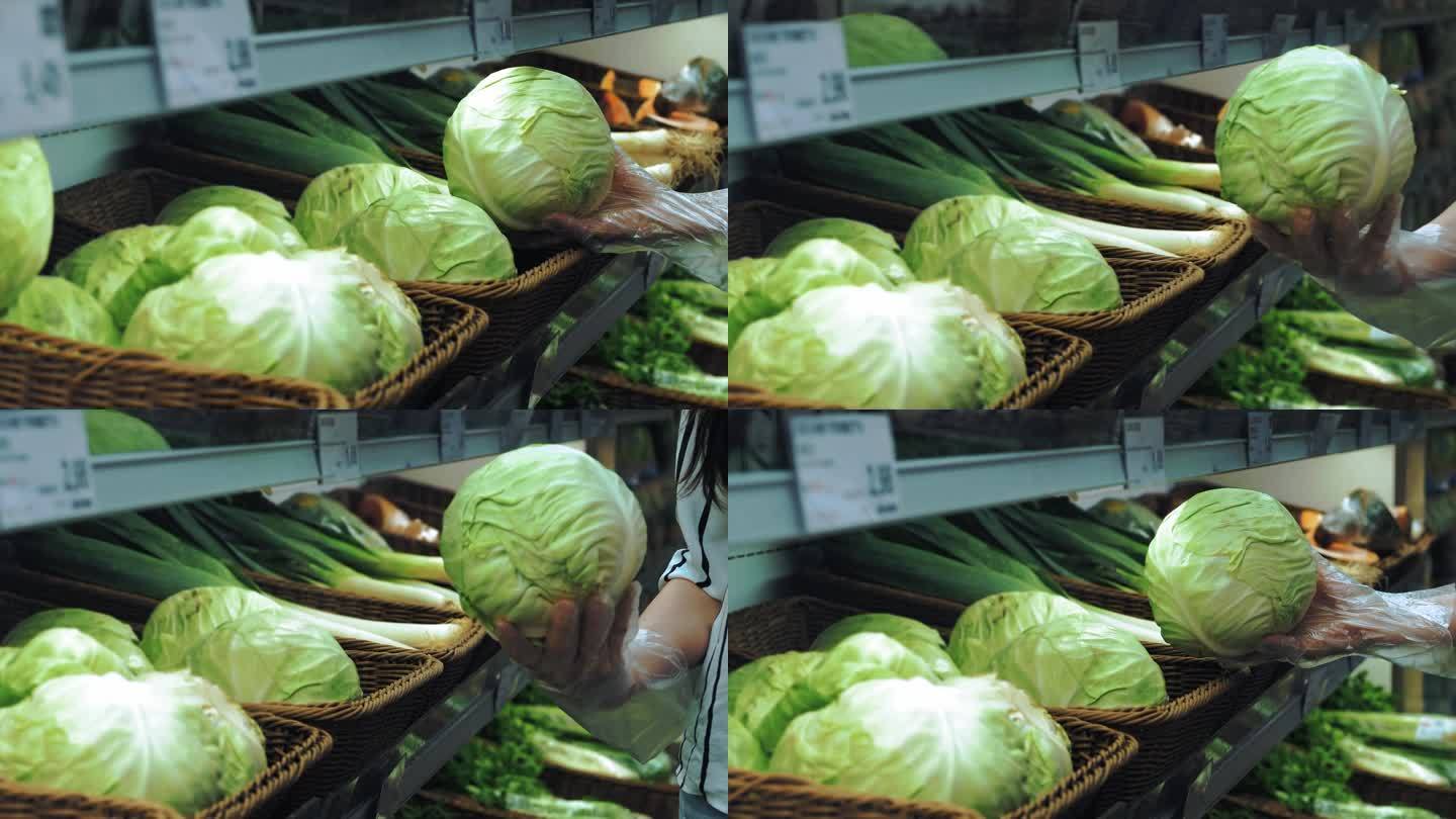 超市里的卷心菜。特写镜头。杂货店柜台上的新鲜卷心菜。一只戴着透明手套的女性手在超市蔬菜部挑选白菜头。