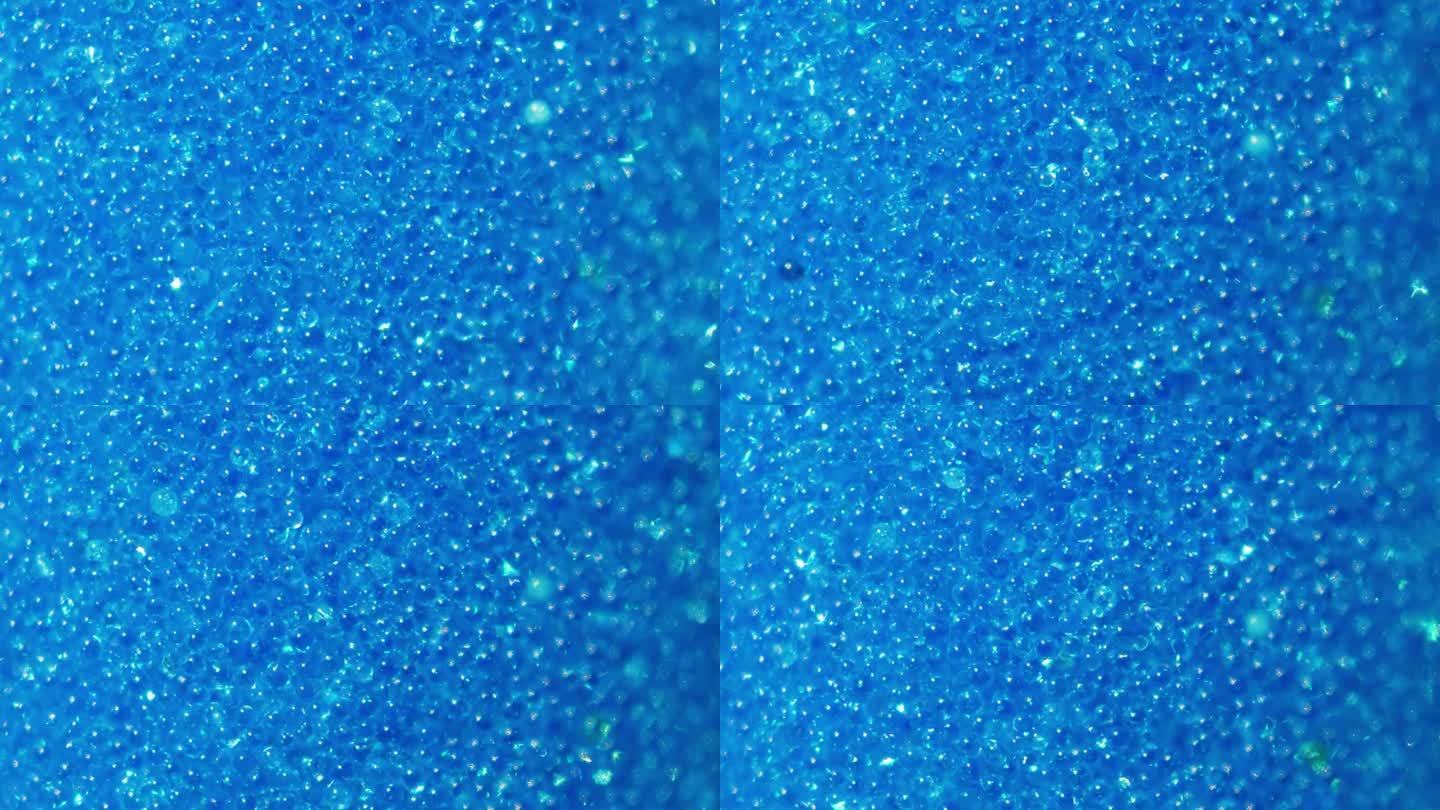 令人惊叹的软蓝色背景制成的小石英珠。沙子慢慢地倒进玻璃烧瓶。沙漏