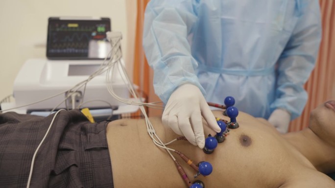 医院护士将电极固定在病人的四肢上，用于心脏病学测试和设备。医生正在为一名男性病人准备取心电图。医生把